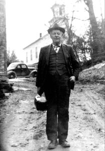  Doc Shaw visiting families in the town of Warren. The current Warren Church can be seen in the background of this photo. Approximate date, 1930 – 1940.